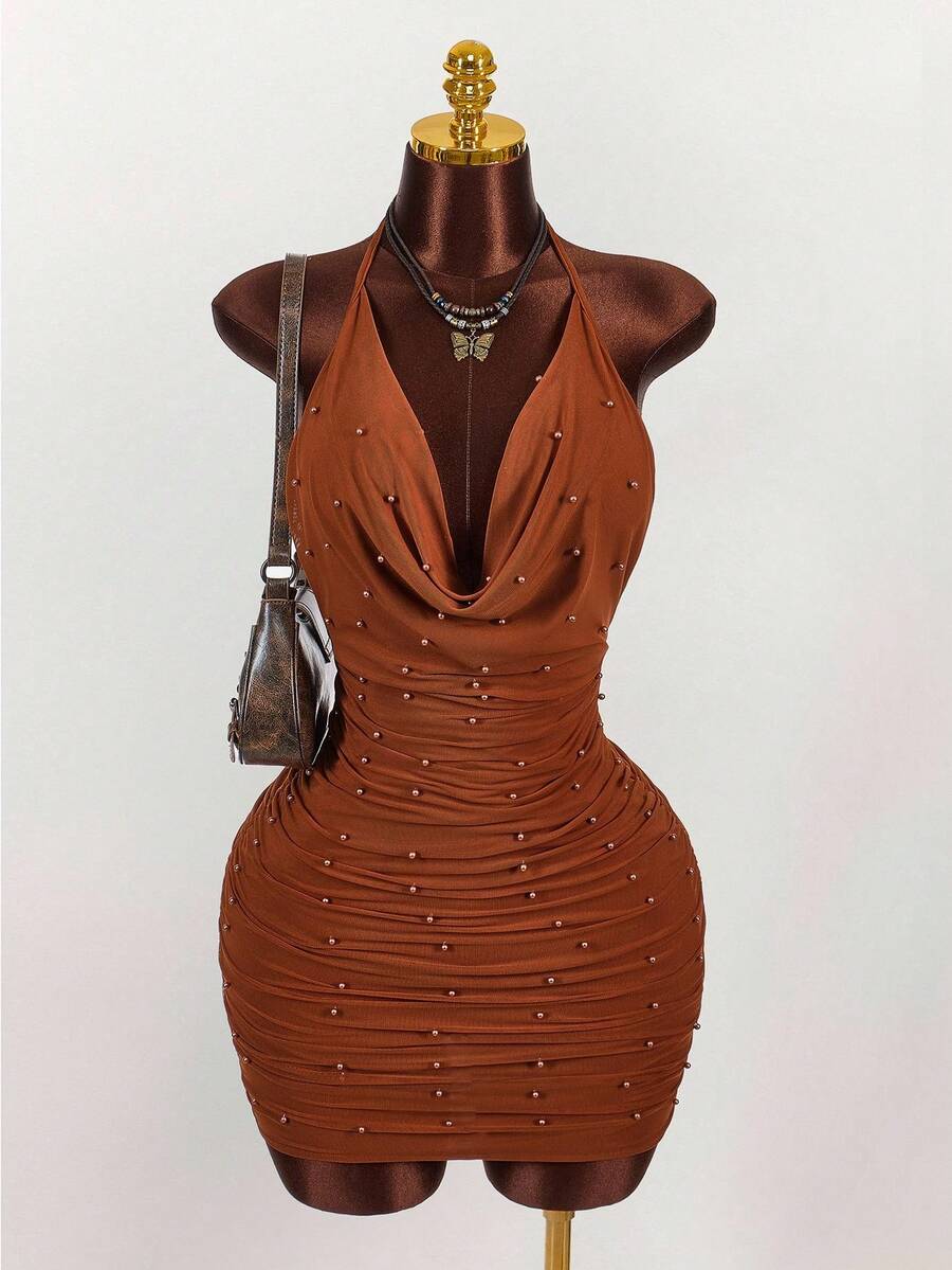 Women's black halter mini dress featuring a backless draped design, semi-sheer mesh fabric, and slim pencil fit.