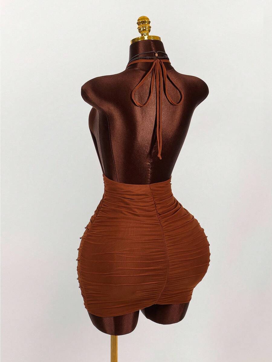 Women's black halter mini dress featuring a backless draped design, semi-sheer mesh fabric, and slim pencil fit.