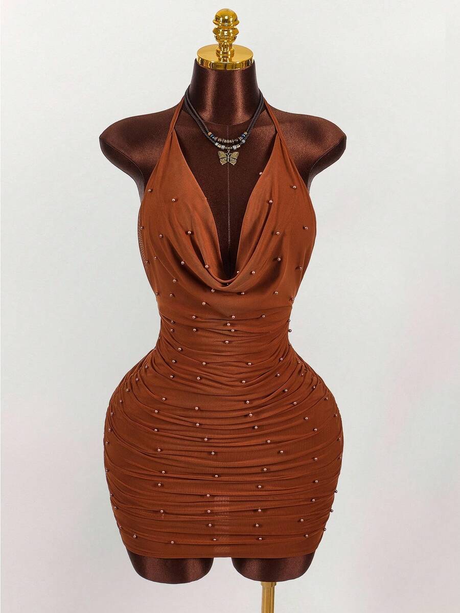 Women's black halter mini dress featuring a backless draped design, semi-sheer mesh fabric, and slim pencil fit.