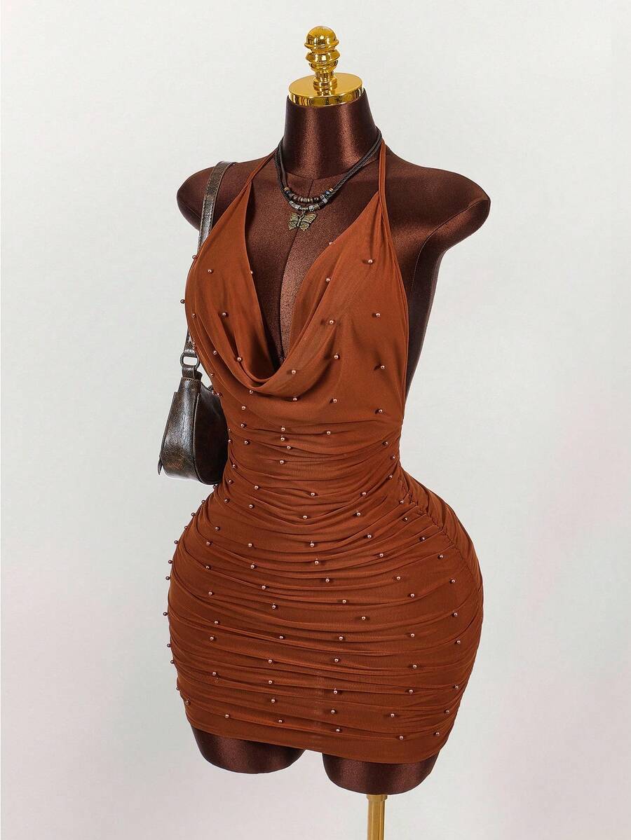Women's black halter mini dress featuring a backless draped design, semi-sheer mesh fabric, and slim pencil fit.