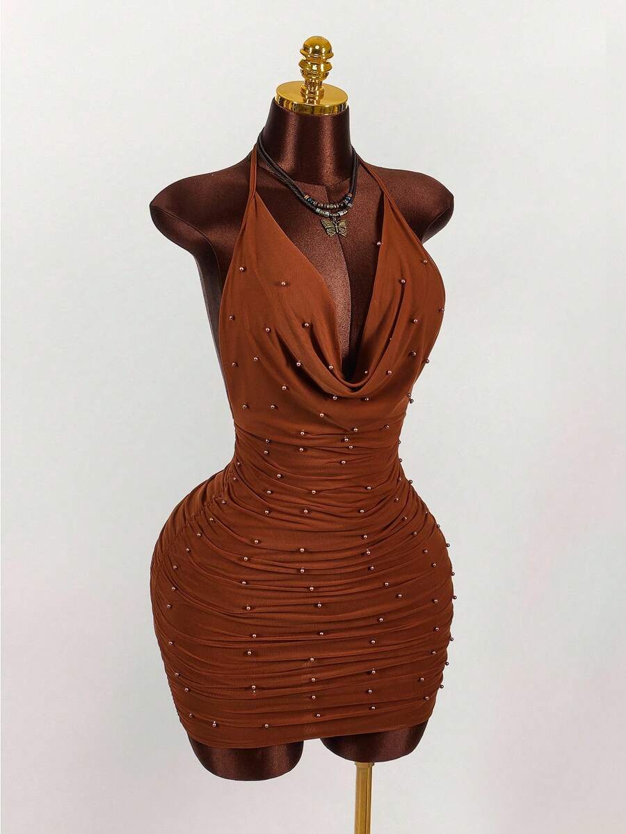 Women's black halter mini dress featuring a backless draped design, semi-sheer mesh fabric, and slim pencil fit.