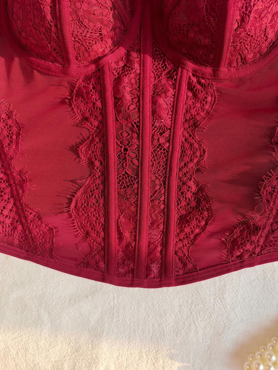 Front view of a black seamless lace camisole crop top featuring delicate spaghetti straps and intricate contrast lace detailing.
