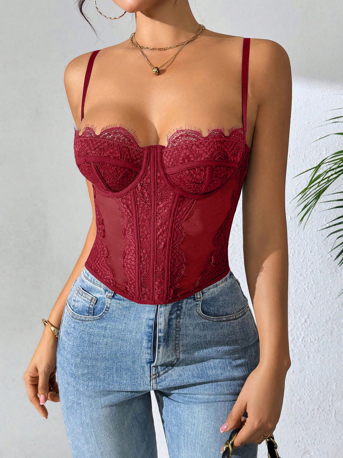 Front view of a black seamless lace camisole crop top featuring delicate spaghetti straps and intricate contrast lace detailing.