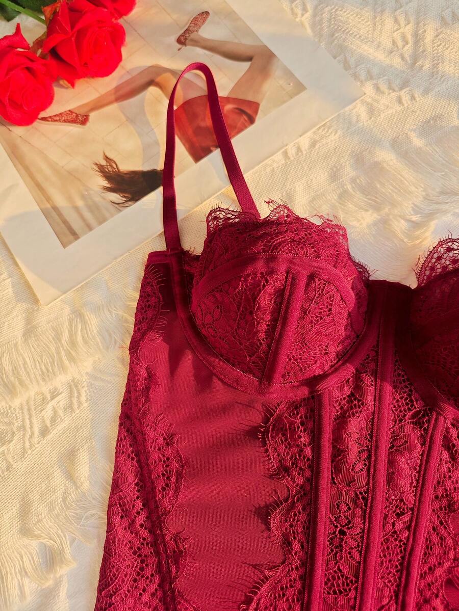Front view of a black seamless lace camisole crop top featuring delicate spaghetti straps and intricate contrast lace detailing.