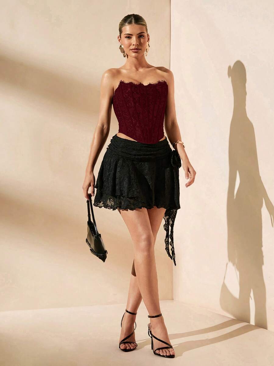 Women's strapless bustier crop top with contrast lace, lace-up detail, and an asymmetric hem in a slim-fit satin finish.