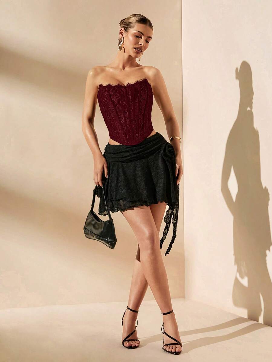 Women's strapless bustier crop top with contrast lace, lace-up detail, and an asymmetric hem in a slim-fit satin finish.