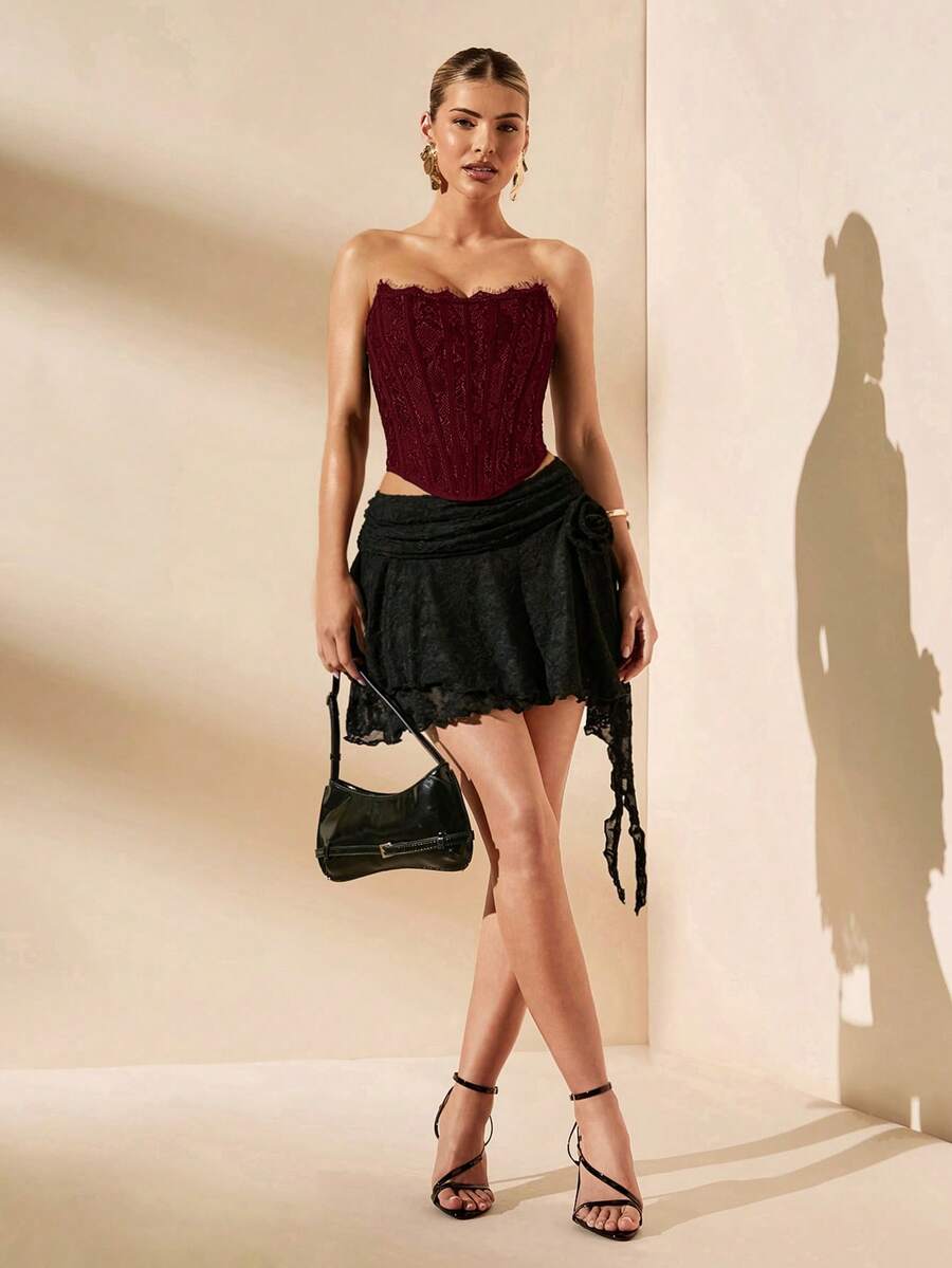 Women's strapless bustier crop top with contrast lace, lace-up detail, and an asymmetric hem in a slim-fit satin finish.