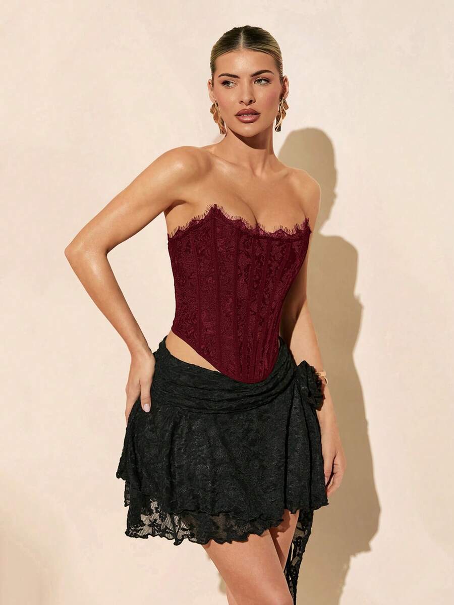 Women's strapless bustier crop top with contrast lace, lace-up detail, and an asymmetric hem in a slim-fit satin finish.