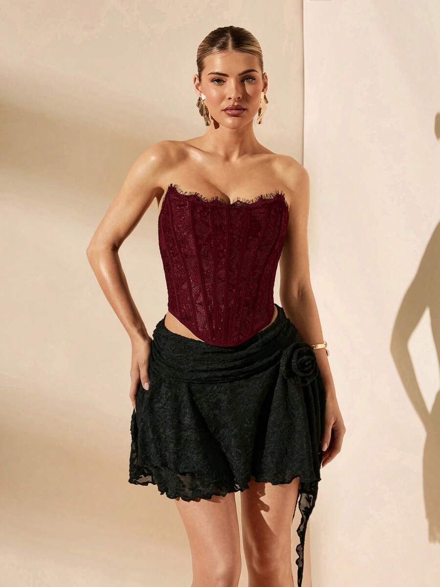 Women's strapless bustier crop top with contrast lace, lace-up detail, and an asymmetric hem in a slim-fit satin finish.
