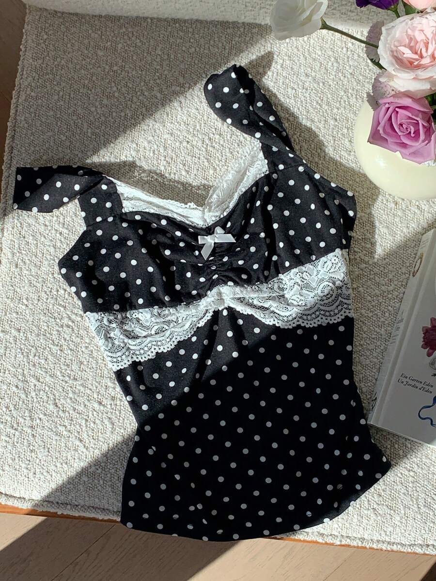 Black and white polka dot knit camisole tank top featuring delicate contrast lace trim, a cute bow accent at the sweetheart neckline, and slender shoulder straps.