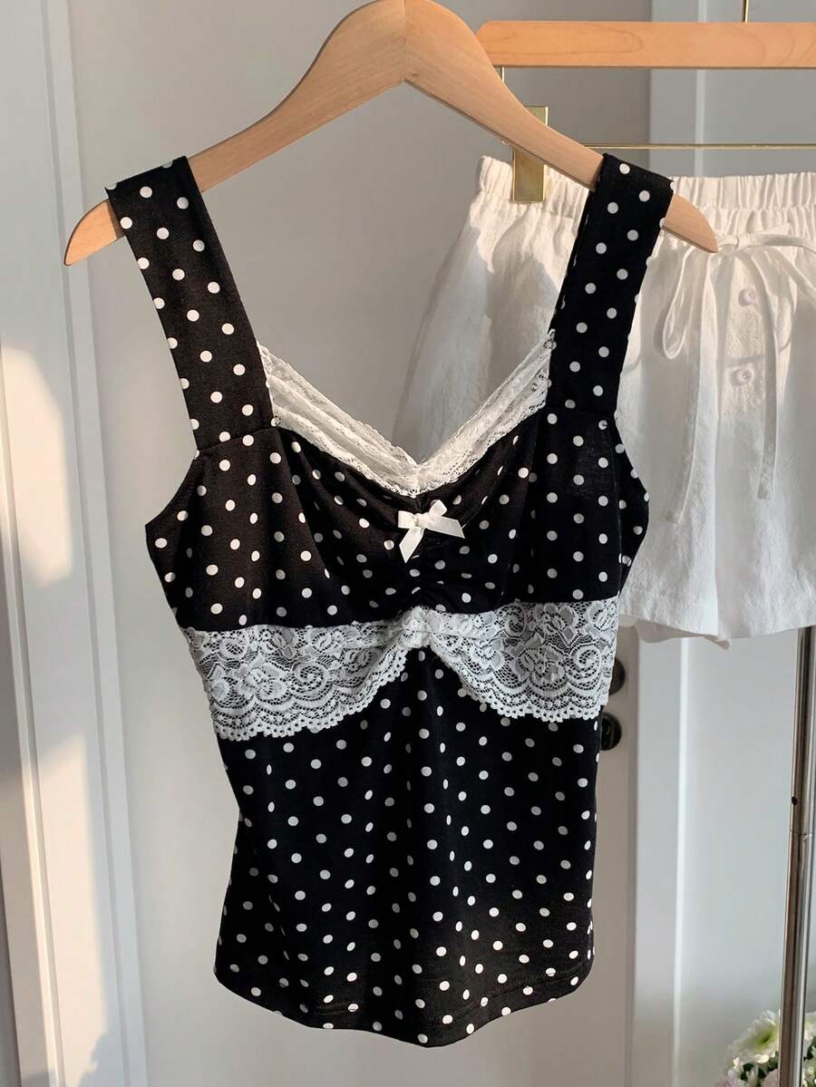 Black and white polka dot knit camisole tank top featuring delicate contrast lace trim, a cute bow accent at the sweetheart neckline, and slender shoulder straps.