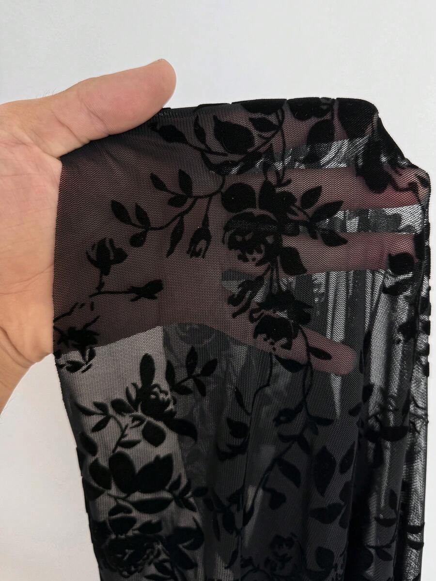 Women's black floral goth maxi dress with an asymmetrical neckline, long sleeves, semi-sheer knitted fabric, and a high split thigh hem in a slim fit bodycon style.