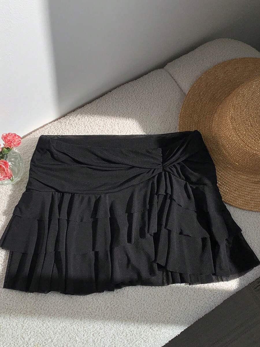 Black tiered ruffle mini cake skirt for women featuring a mid-waist pleated design and layered ruffle hem.