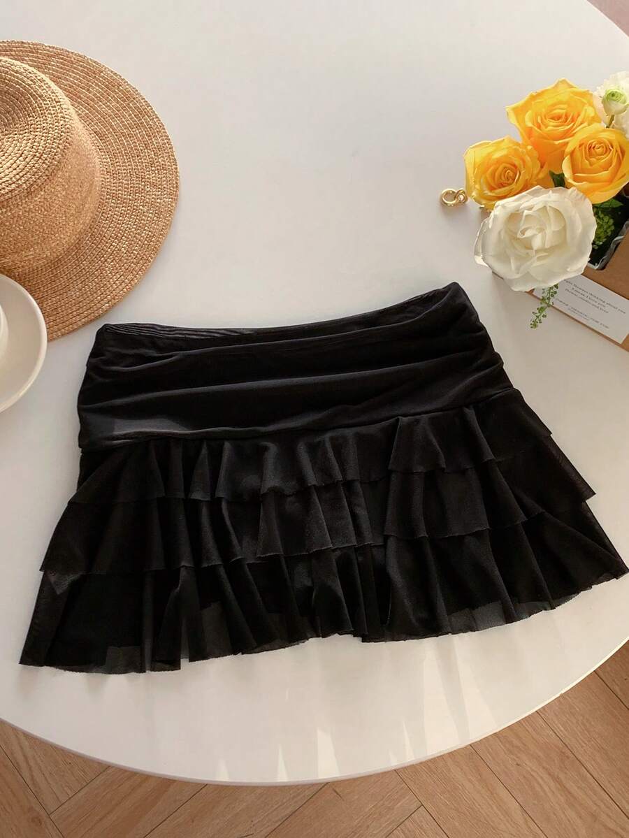 Black tiered ruffle mini cake skirt for women featuring a mid-waist pleated design and layered ruffle hem.