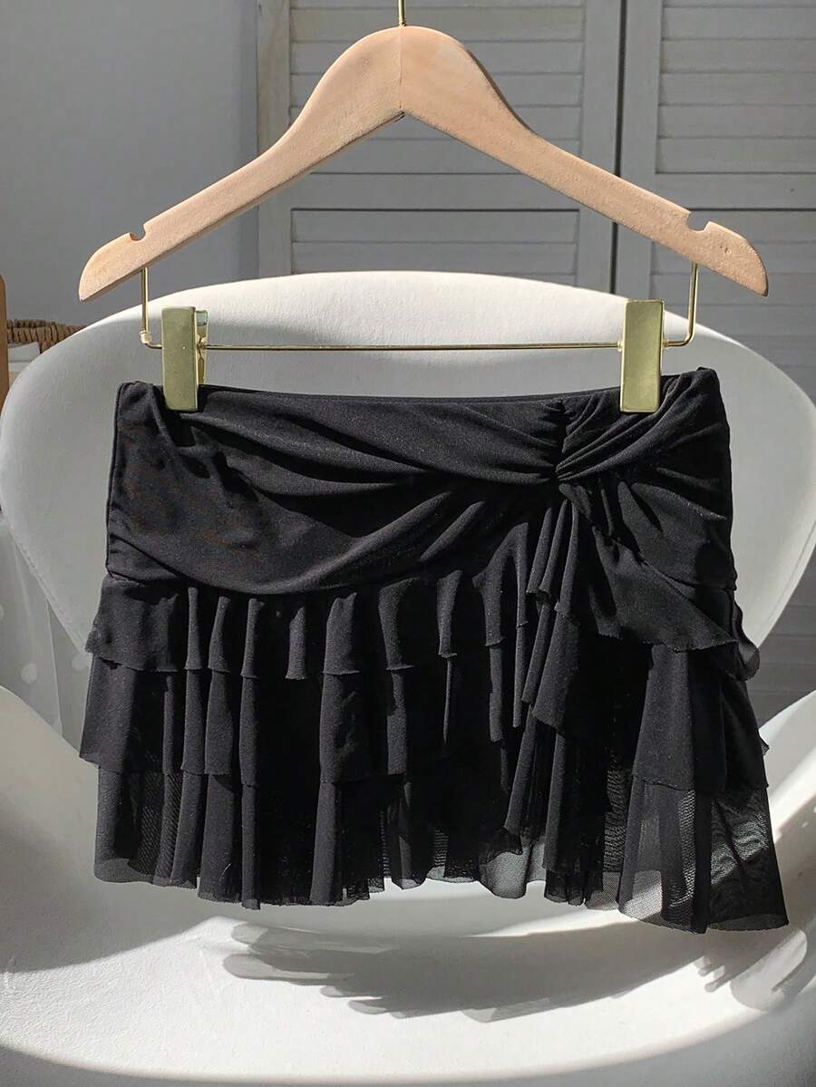 Black tiered ruffle mini cake skirt for women featuring a mid-waist pleated design and layered ruffle hem.