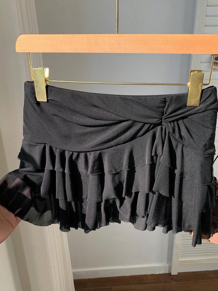 Black tiered ruffle mini cake skirt for women featuring a mid-waist pleated design and layered ruffle hem.