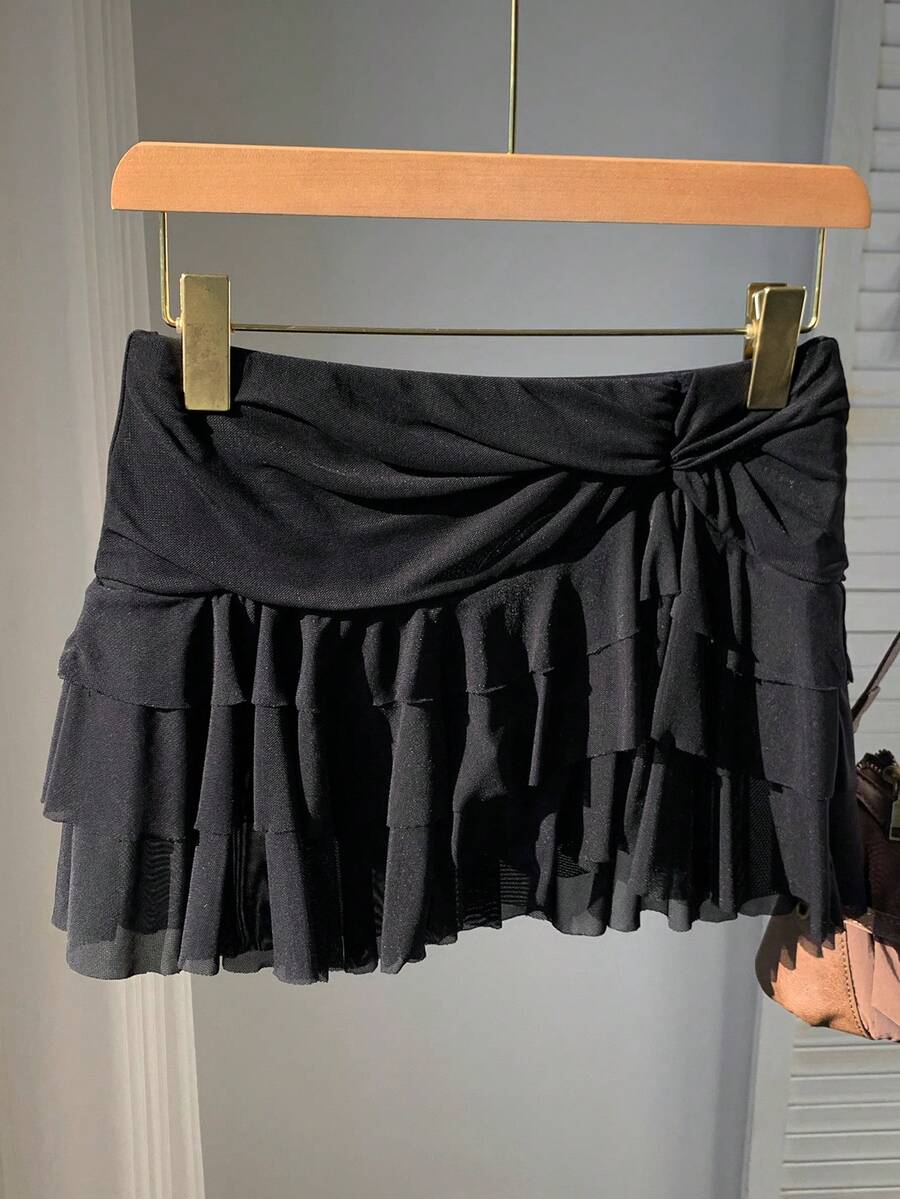 Black tiered ruffle mini cake skirt for women featuring a mid-waist pleated design and layered ruffle hem.