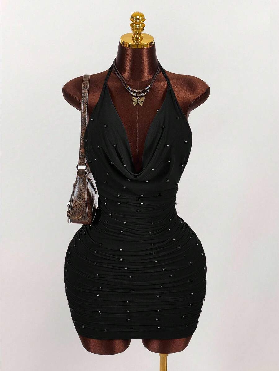 Women's black halter mini dress featuring a backless draped design, semi-sheer mesh fabric, and slim pencil fit.