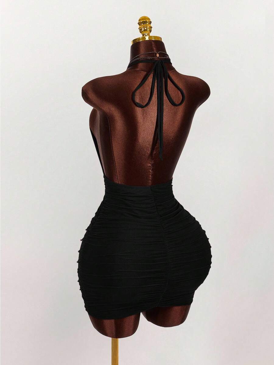 Women's black halter mini dress featuring a backless draped design, semi-sheer mesh fabric, and slim pencil fit.