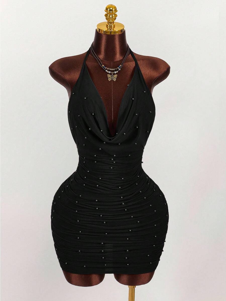 Women's black halter mini dress featuring a backless draped design, semi-sheer mesh fabric, and slim pencil fit.