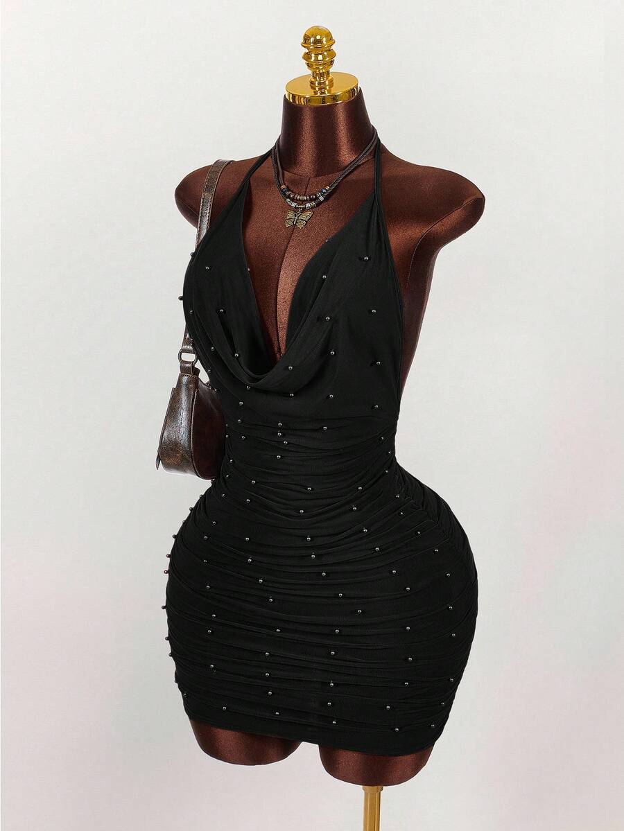 Women's black halter mini dress featuring a backless draped design, semi-sheer mesh fabric, and slim pencil fit.
