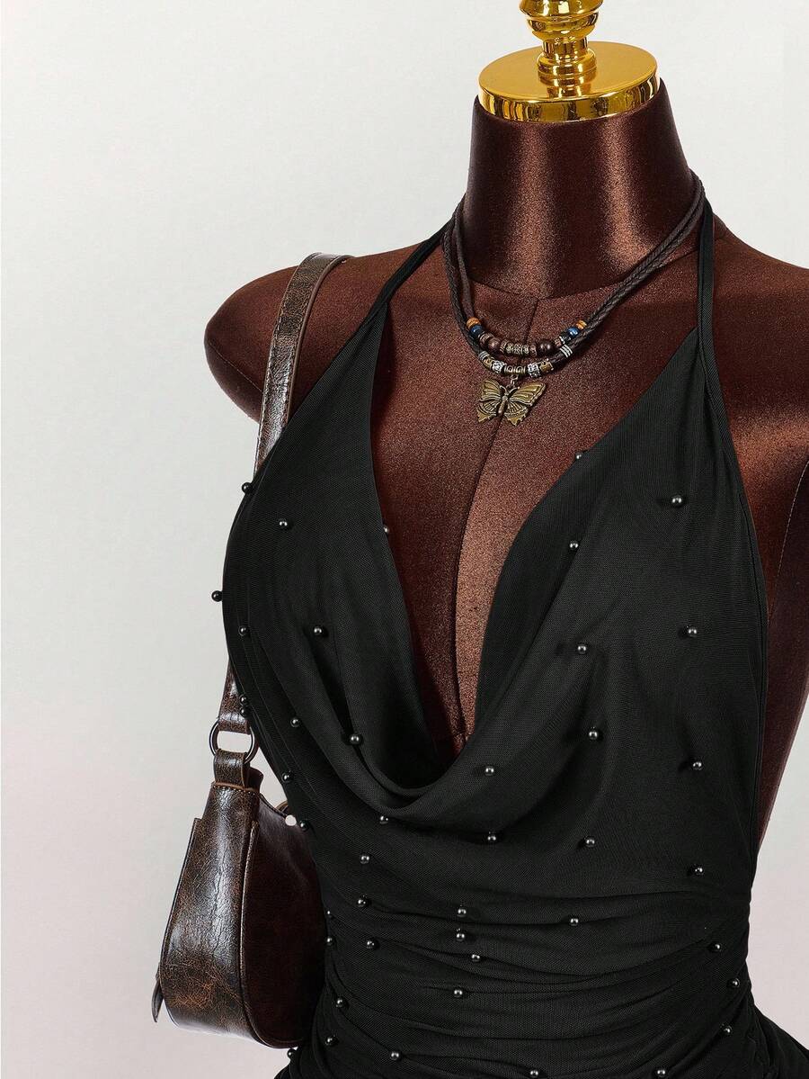 Women's black halter mini dress featuring a backless draped design, semi-sheer mesh fabric, and slim pencil fit.