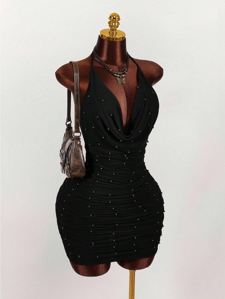 Women's black halter mini dress featuring a backless draped design, semi-sheer mesh fabric, and slim pencil fit.