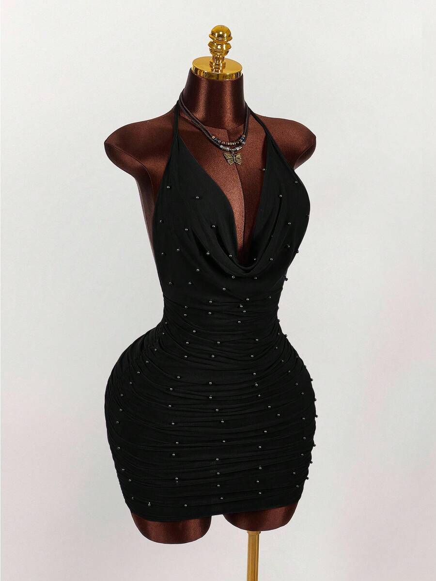 Women's black halter mini dress featuring a backless draped design, semi-sheer mesh fabric, and slim pencil fit.