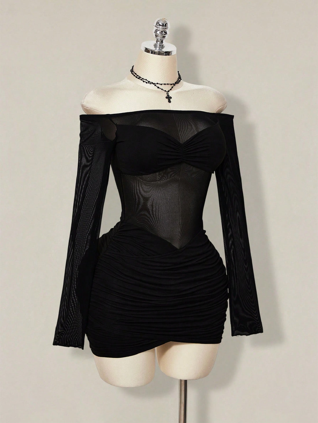 Women's black off-shoulder mini dress featuring sheer mesh patchwork details, ruched bodycon fit, and long flare sleeves.