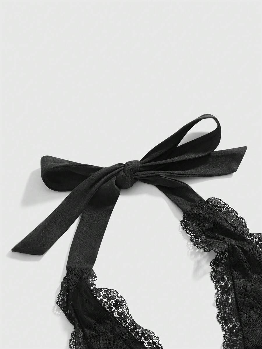 Women's black fitted halter neck camisole featuring contrast lace details, a V-neckline, knot detail, and backless design.