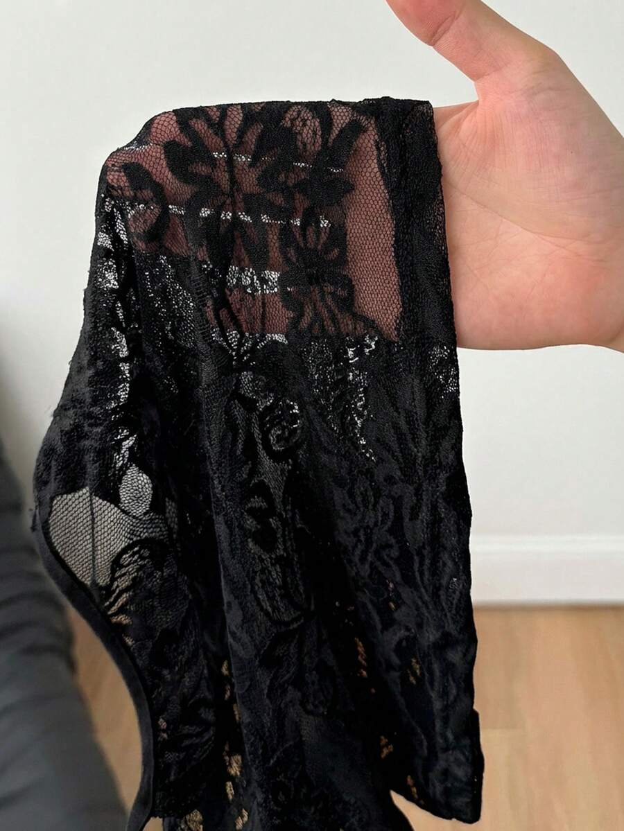 Women's black lace cami crop top featuring spaghetti straps, semi-sheer plant pattern fabric, and a backless design.