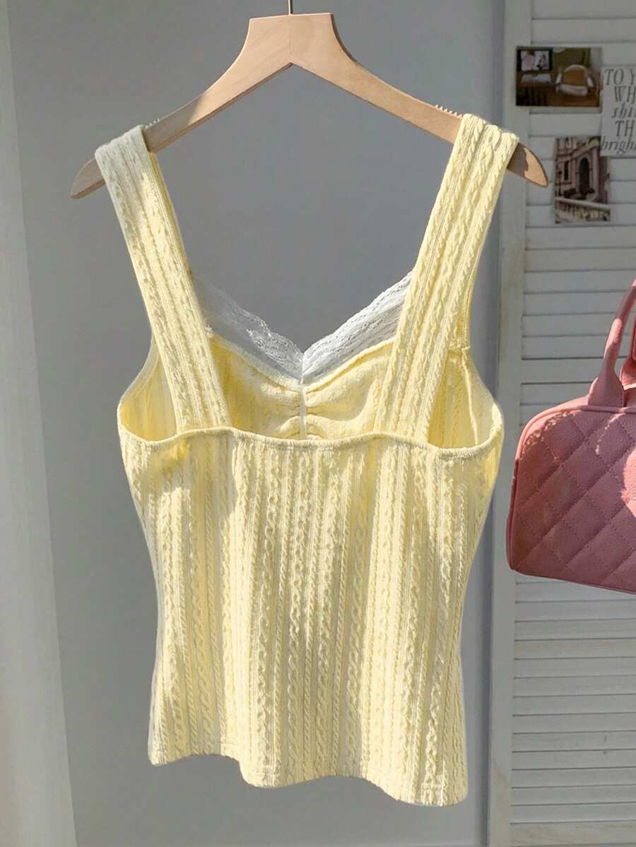 Black and white polka dot knit camisole tank top featuring delicate contrast lace trim, a cute bow accent at the sweetheart neckline, and slender shoulder straps.