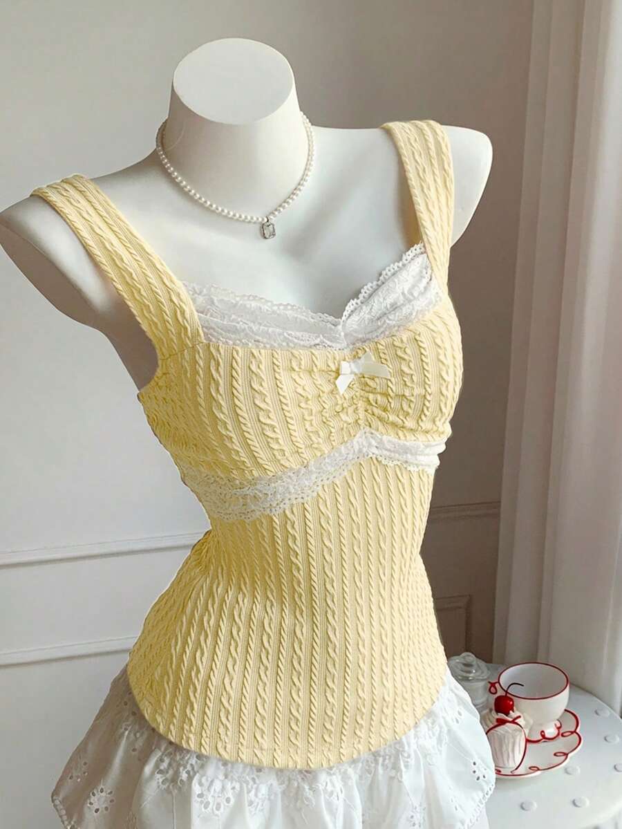 Black and white polka dot knit camisole tank top featuring delicate contrast lace trim, a cute bow accent at the sweetheart neckline, and slender shoulder straps.