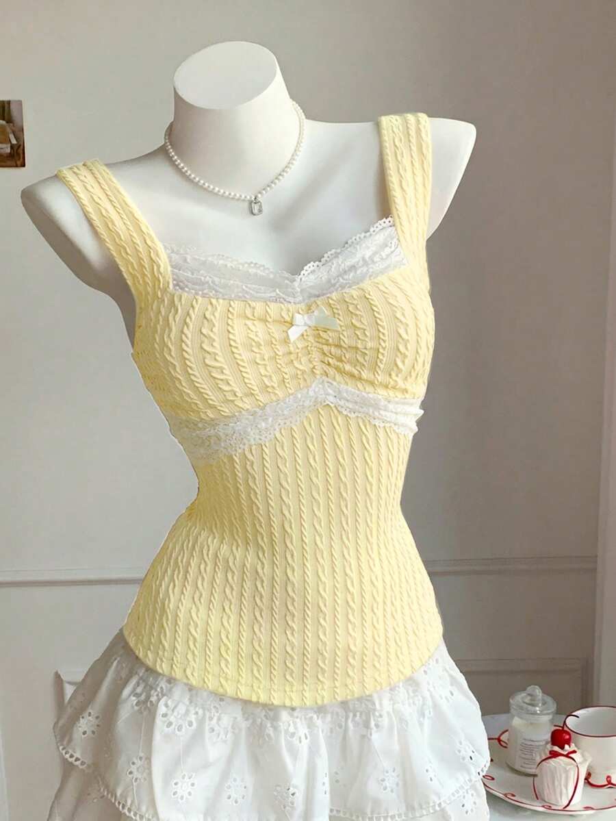 Black and white polka dot knit camisole tank top featuring delicate contrast lace trim, a cute bow accent at the sweetheart neckline, and slender shoulder straps.