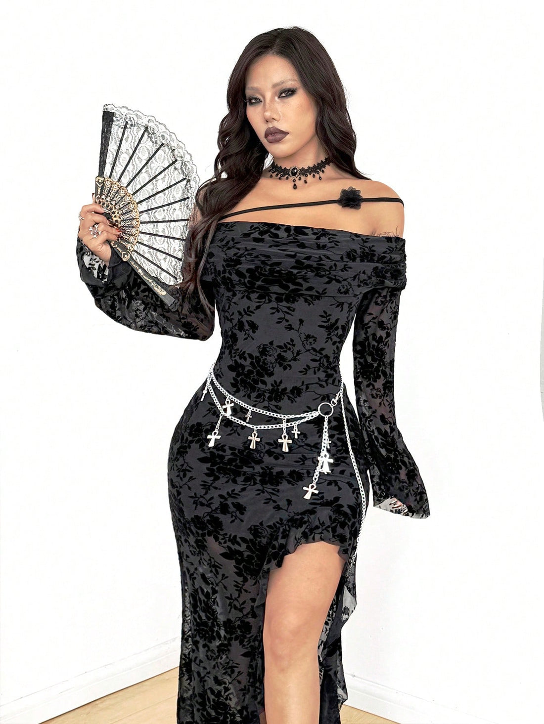 Women's black floral goth maxi dress with an asymmetrical neckline, long sleeves, semi-sheer knitted fabric, and a high split thigh hem in a slim fit bodycon style.