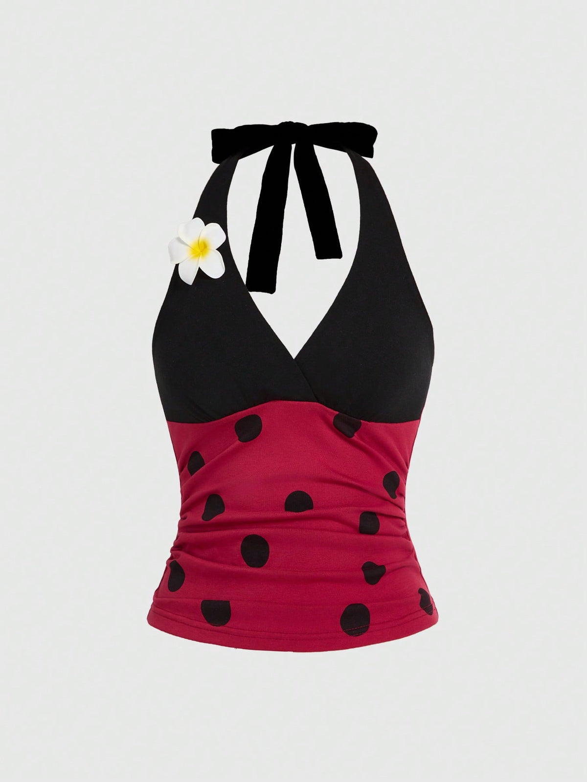Black and white polka dot halter neck tank top featuring a backless design with ruched knot details and daisy accent.