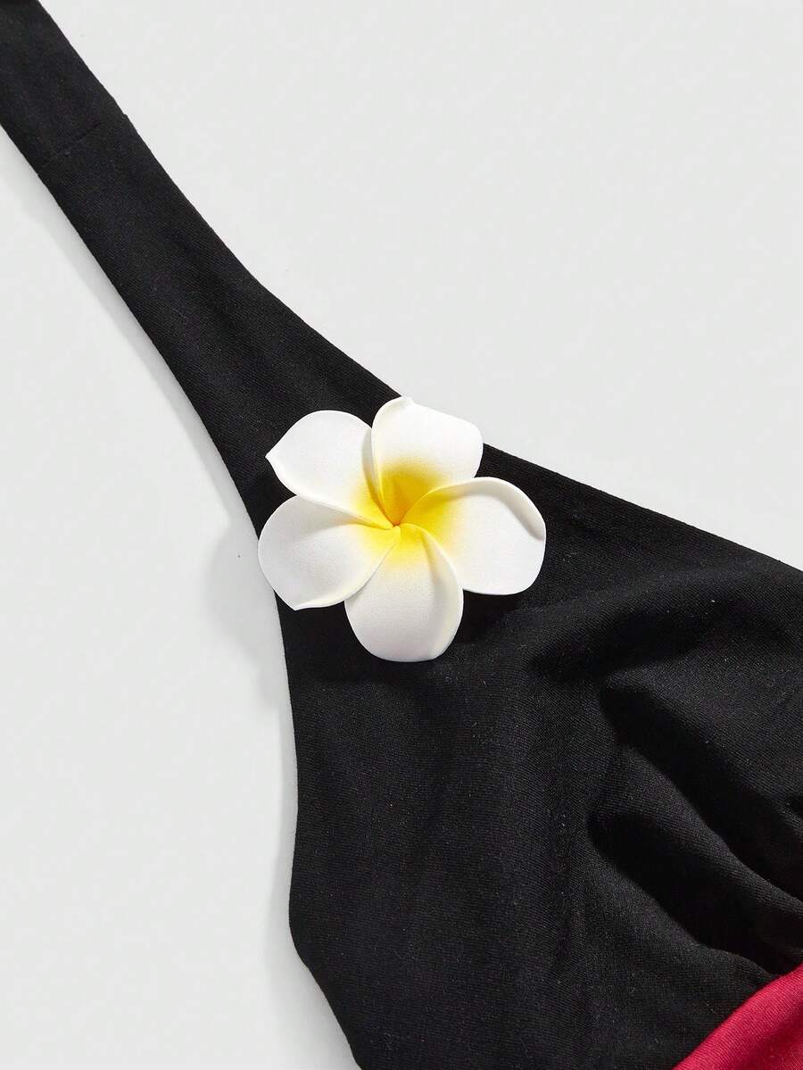 Black and white polka dot halter neck tank top featuring a backless design with ruched knot details and daisy accent.