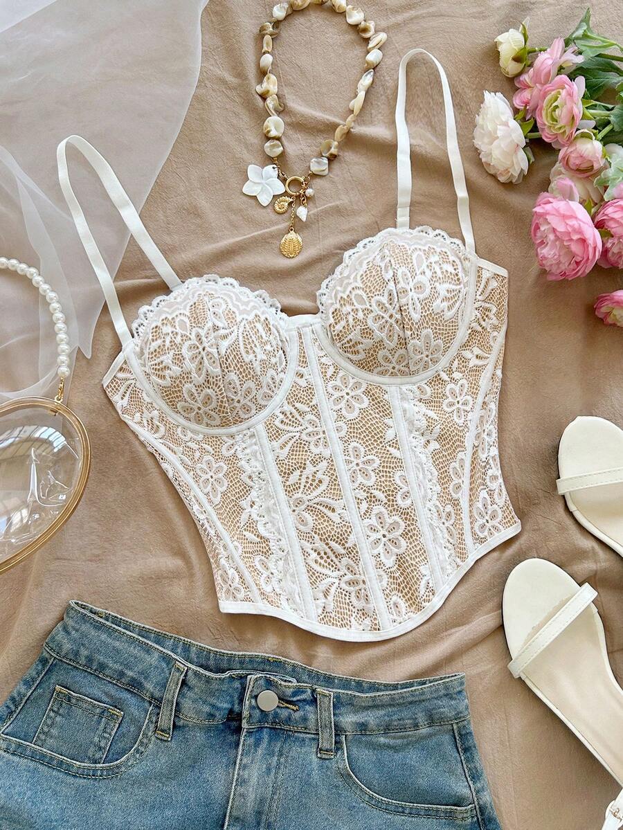 Women's lace bustier camisole top with spaghetti straps, contrast lace, lace-up detail, and an asymmetrical hem in a slim fit design.