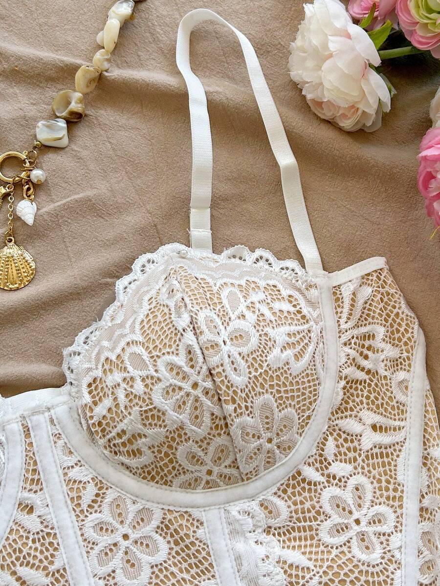 Women's lace bustier camisole top with spaghetti straps, contrast lace, lace-up detail, and an asymmetrical hem in a slim fit design.