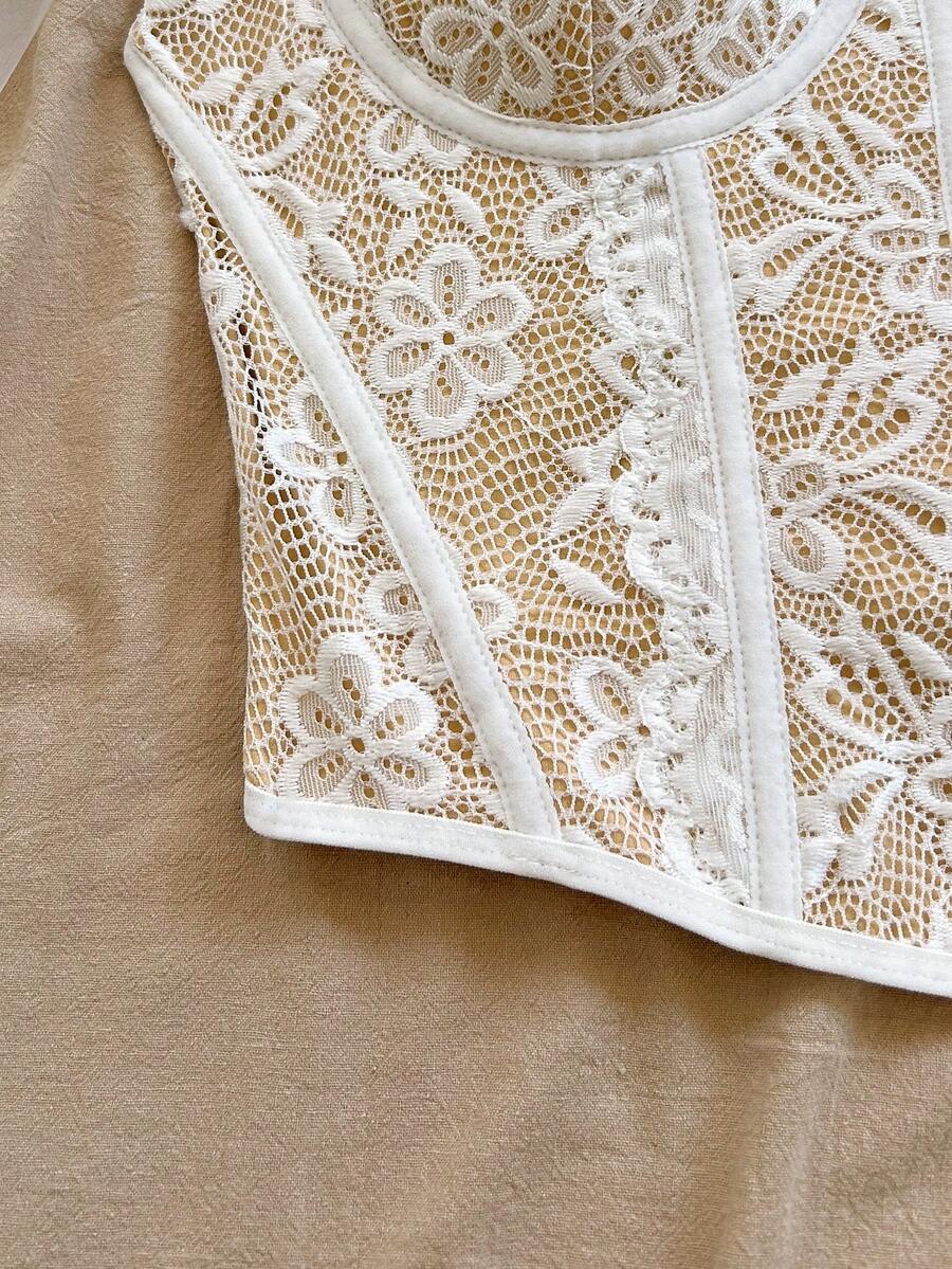 Women's lace bustier camisole top with spaghetti straps, contrast lace, lace-up detail, and an asymmetrical hem in a slim fit design.