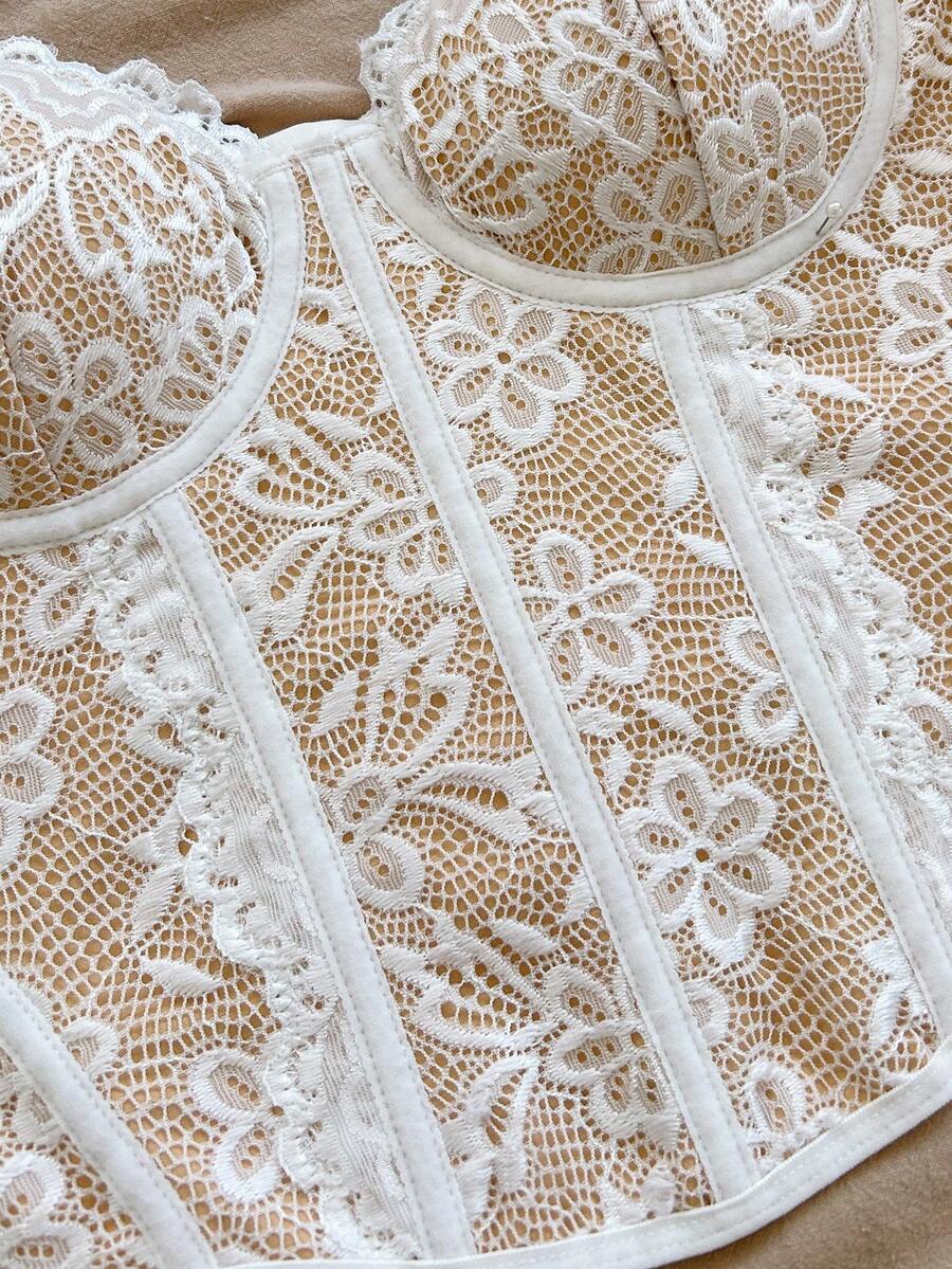 Women's lace bustier camisole top with spaghetti straps, contrast lace, lace-up detail, and an asymmetrical hem in a slim fit design.