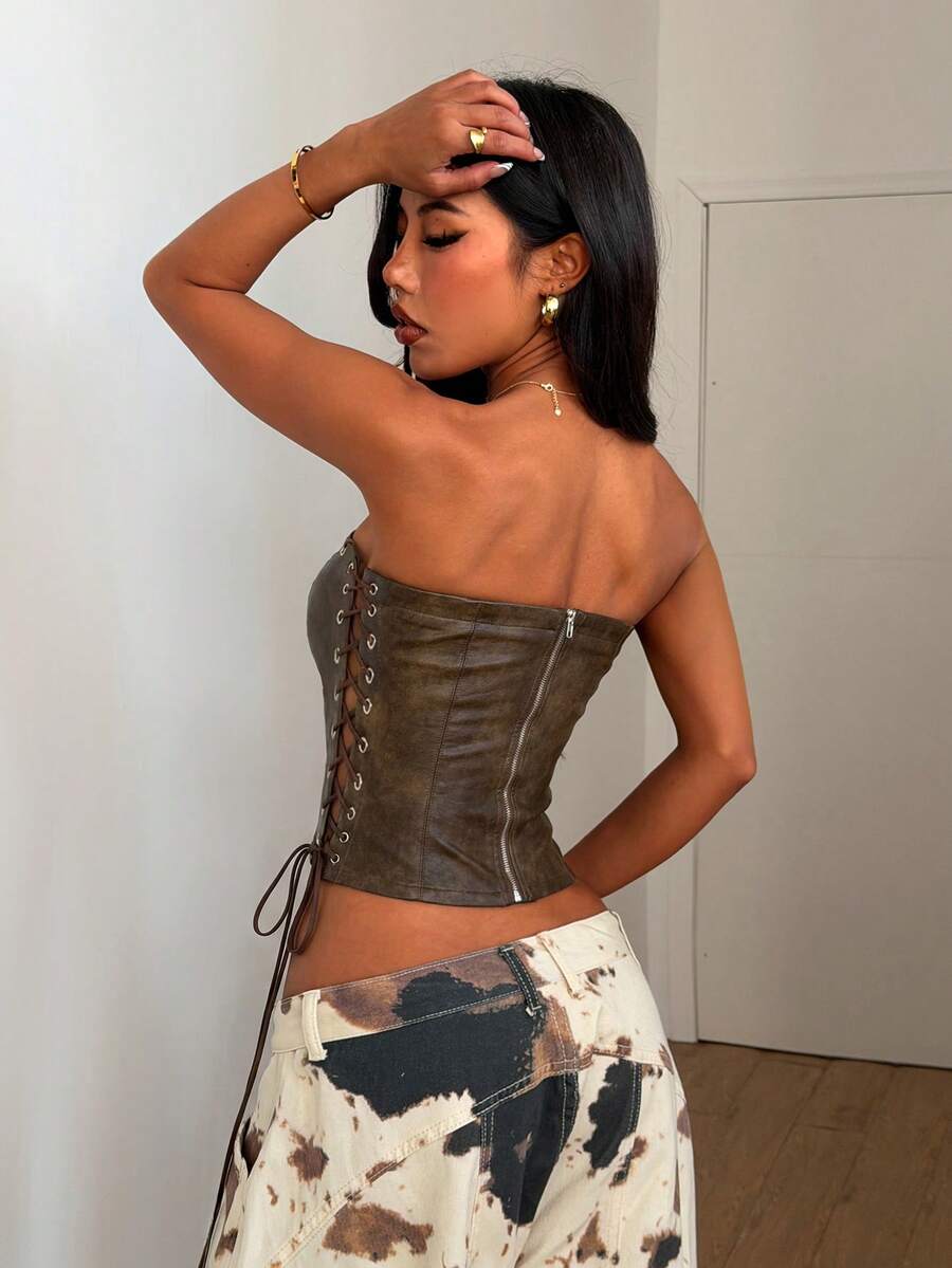 Women’s coffee brown faux leather lace-up crop top with strapless neckline, slit hem, and slim fitted silhouette for festival and nightlife wear.
