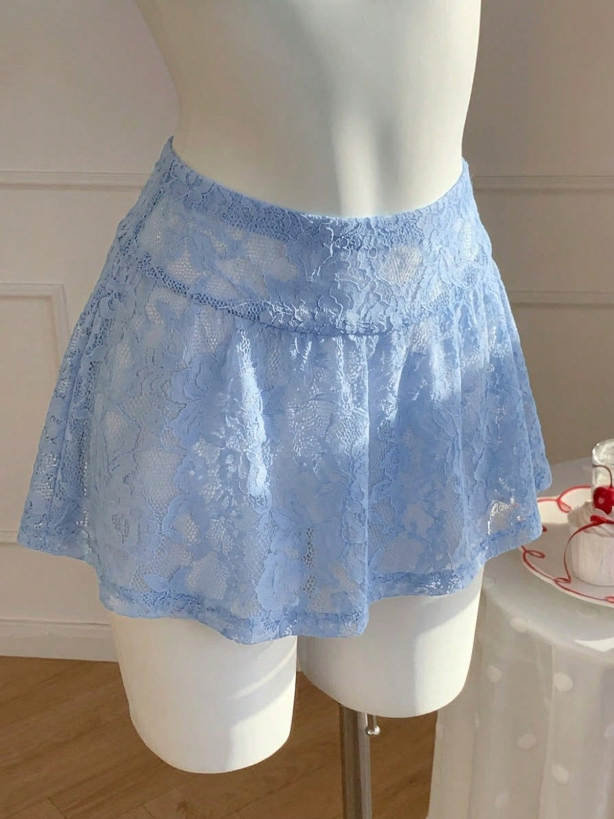 Women's black semi-sheer knitted lace mini skirt featuring a flared ruffle hem and low waist design
