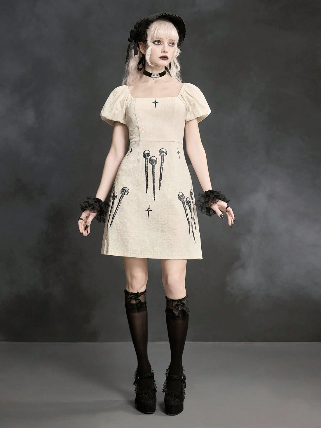 White Goth mini skater dress for women featuring dark skull graphic print, square neckline, short puff sleeves, and lace-up detail.