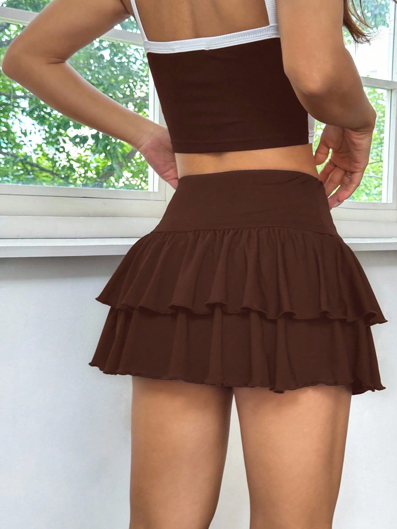 Black low waist knit mini skirt featuring a tiered ruffle hem and skinny high stretch fit.