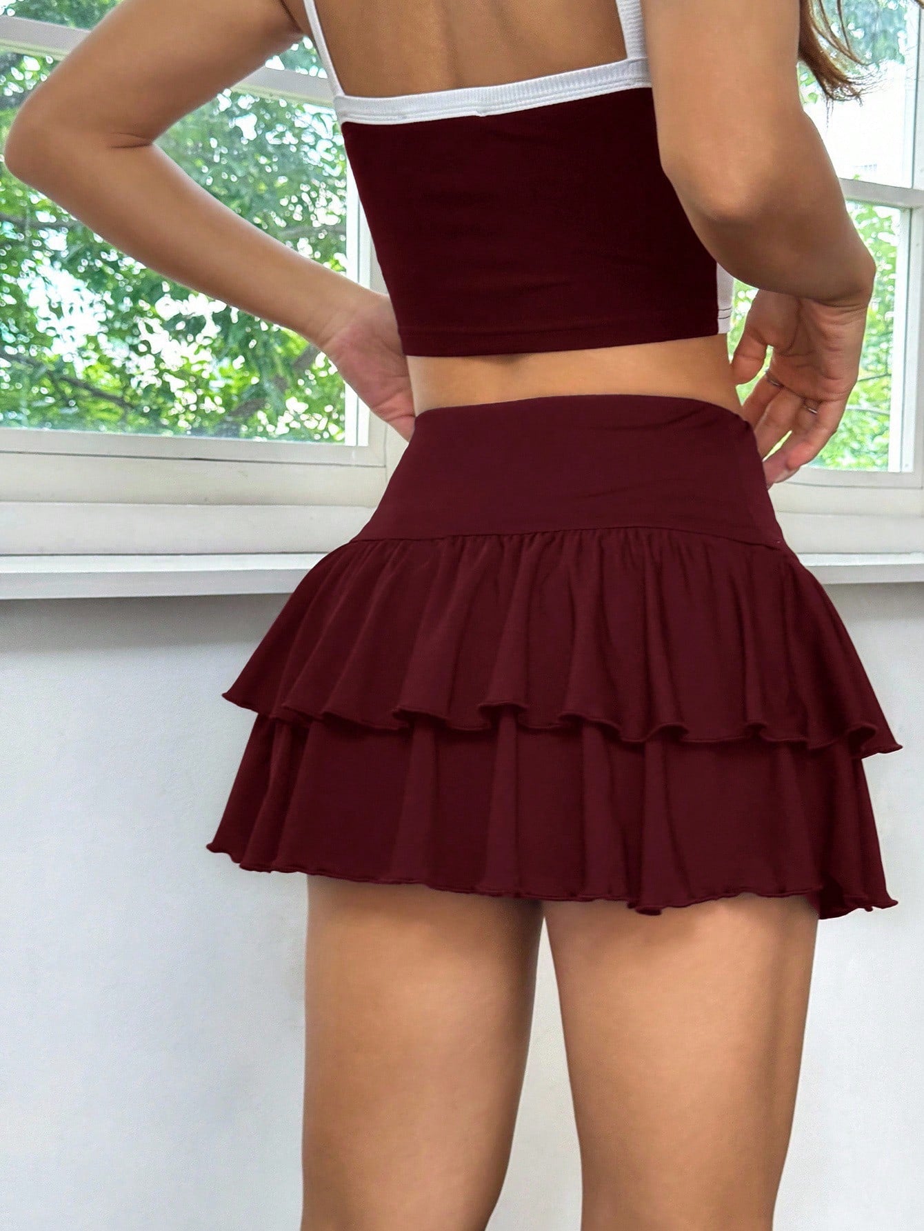 Black low waist knit mini skirt featuring a tiered ruffle hem and skinny high stretch fit.