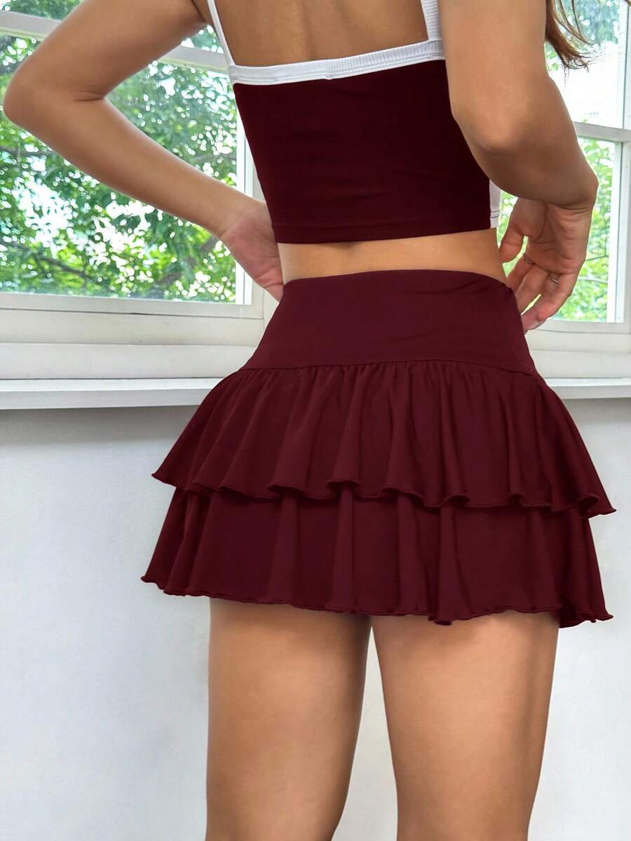 Black low waist knit mini skirt featuring a tiered ruffle hem and skinny high stretch fit.