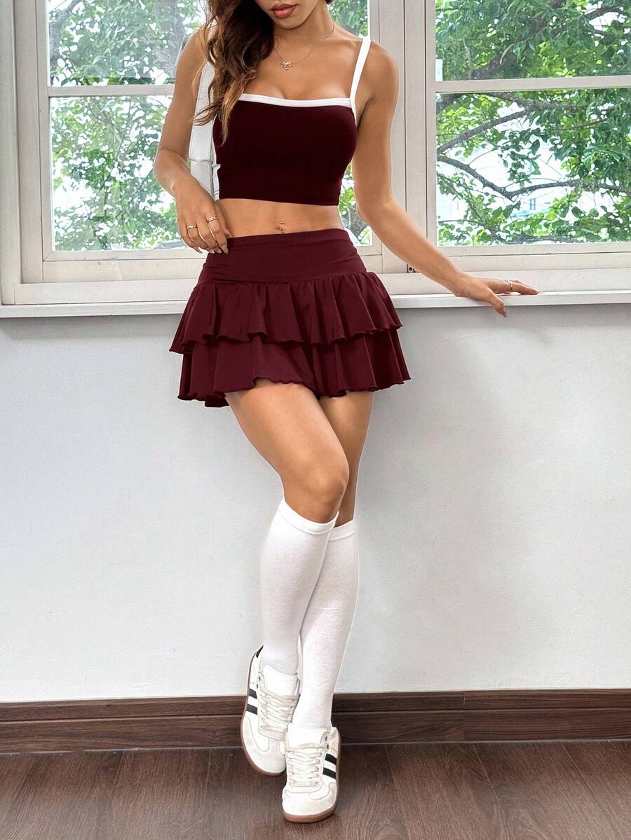Black low waist knit mini skirt featuring a tiered ruffle hem and skinny high stretch fit.
