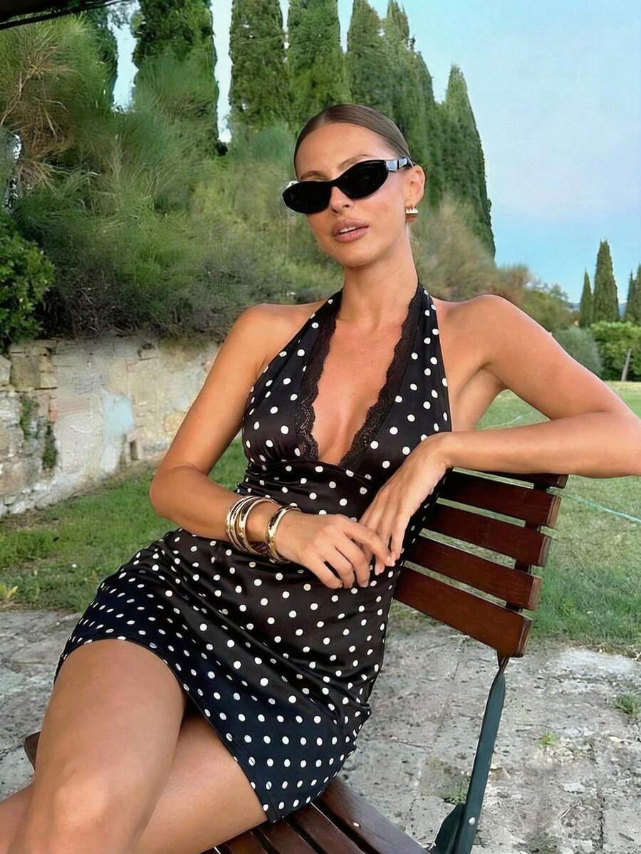 Woman wearing a black and white polka dot lace halter mini dress featuring a backless bodycon fit.