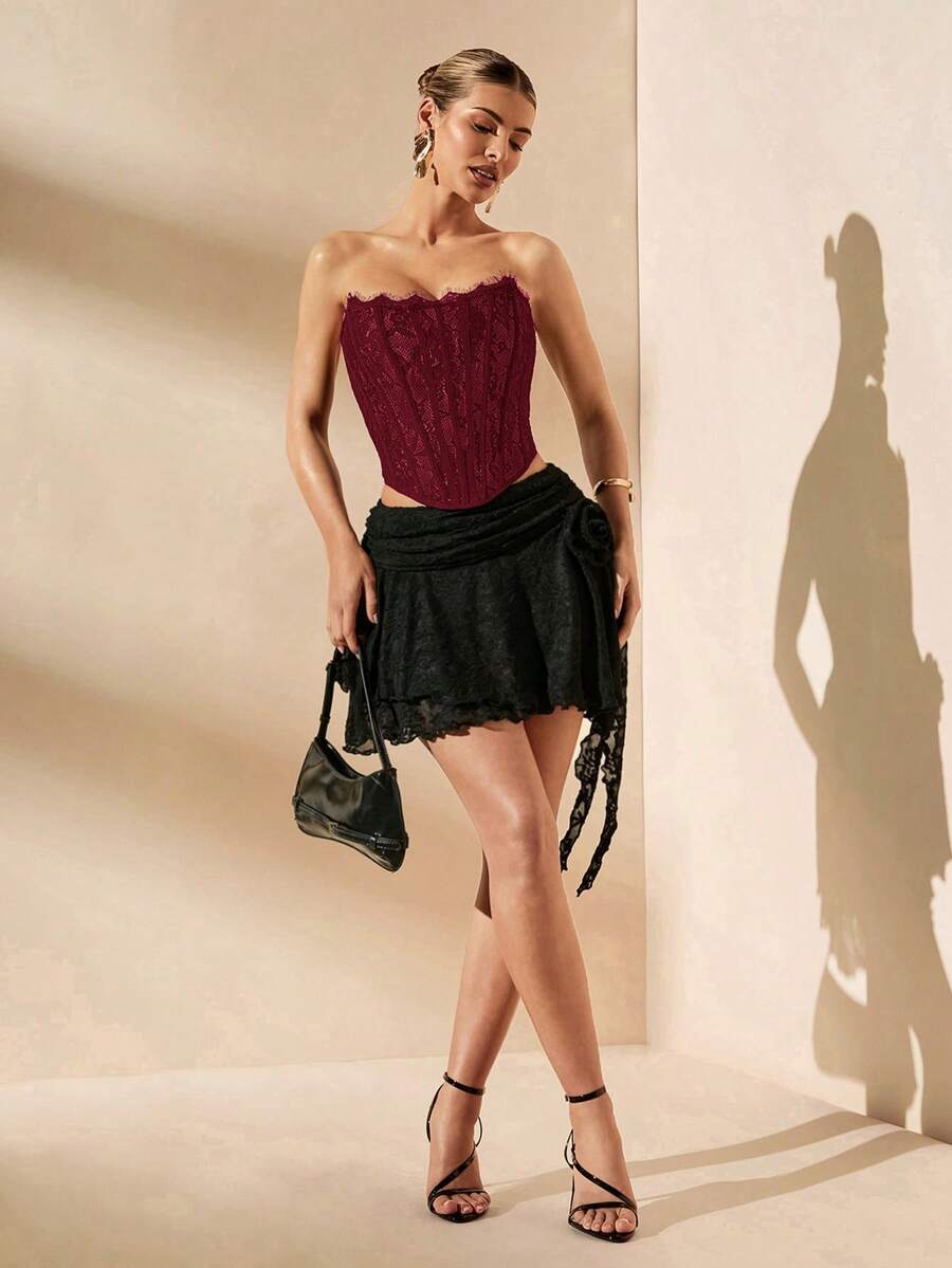 Women's strapless bustier crop top with contrast lace, lace-up detail, and an asymmetric hem in a slim-fit satin finish.